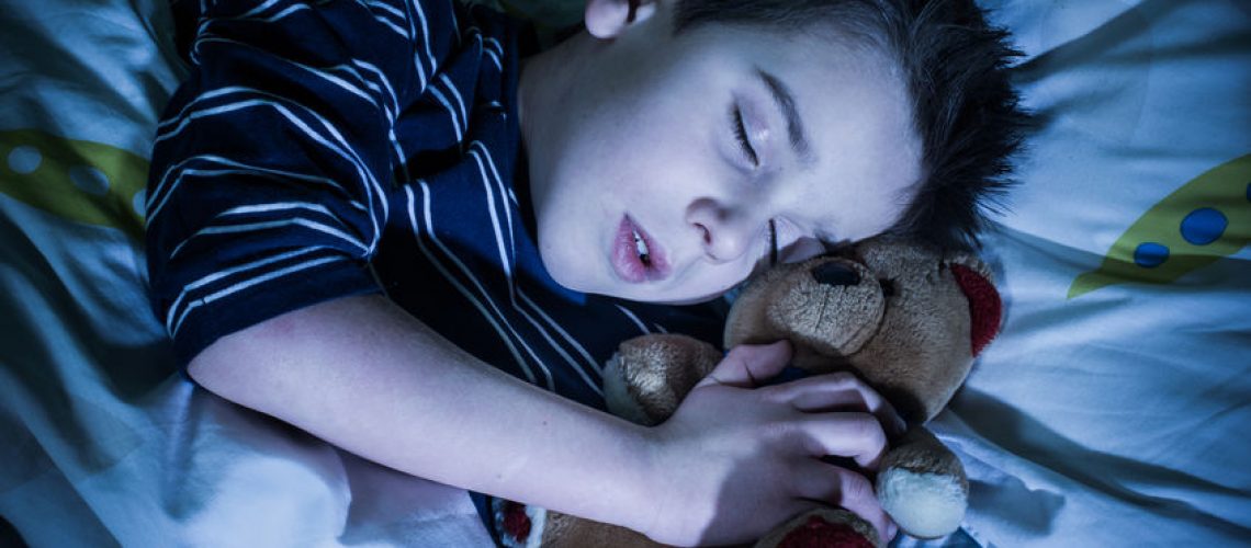 Sleeping child with his toy bear.